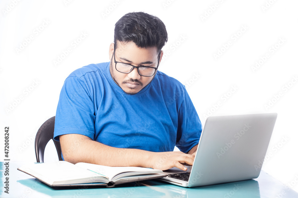 student typing on laptop looking at notebook student typing on laptop looking at notebook