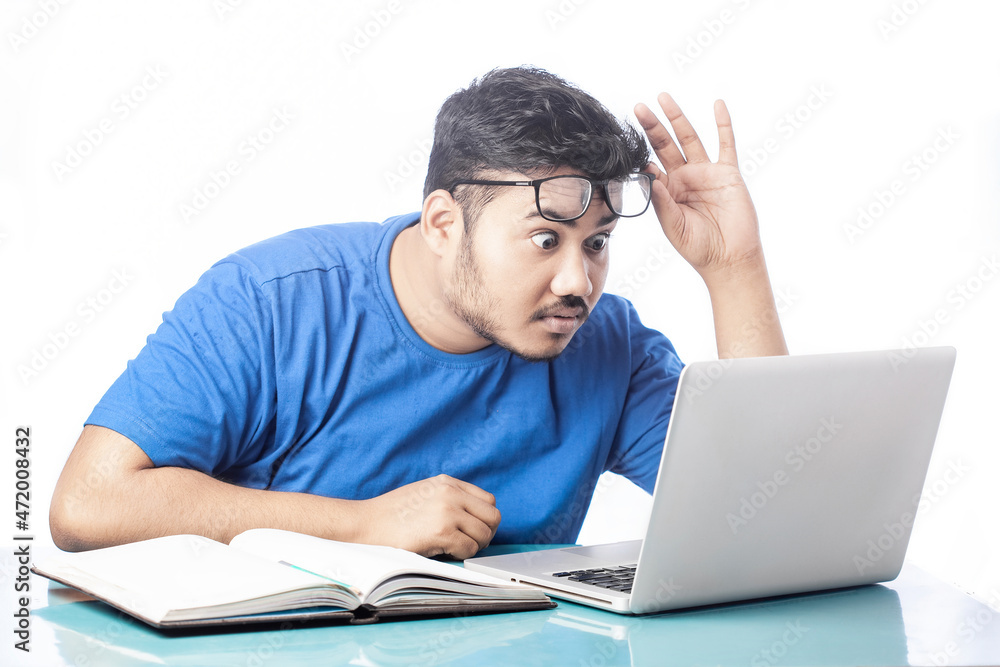 shocked man looking at laptop screen by taking off eyeglass shocked man looking at laptop screen by taking off eyeglass