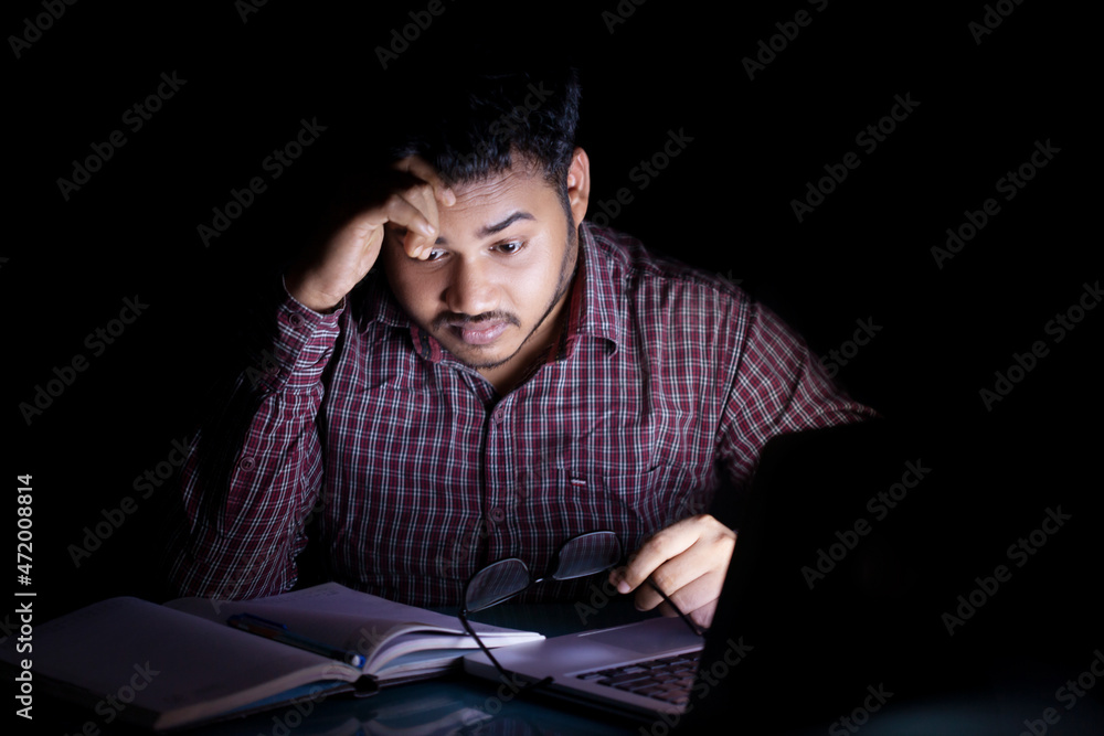student studying and feeling tensed at mid night in front of a laptop screen
