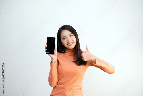 Attractive Asian girl portrait, wearing orange shirt, holding smartphone, smiling face, showing emotion, for communication, advertisement, copy space.