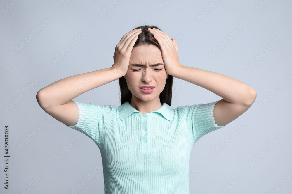 Young woman suffering from headache on light background Young woman suffering from headache on light background