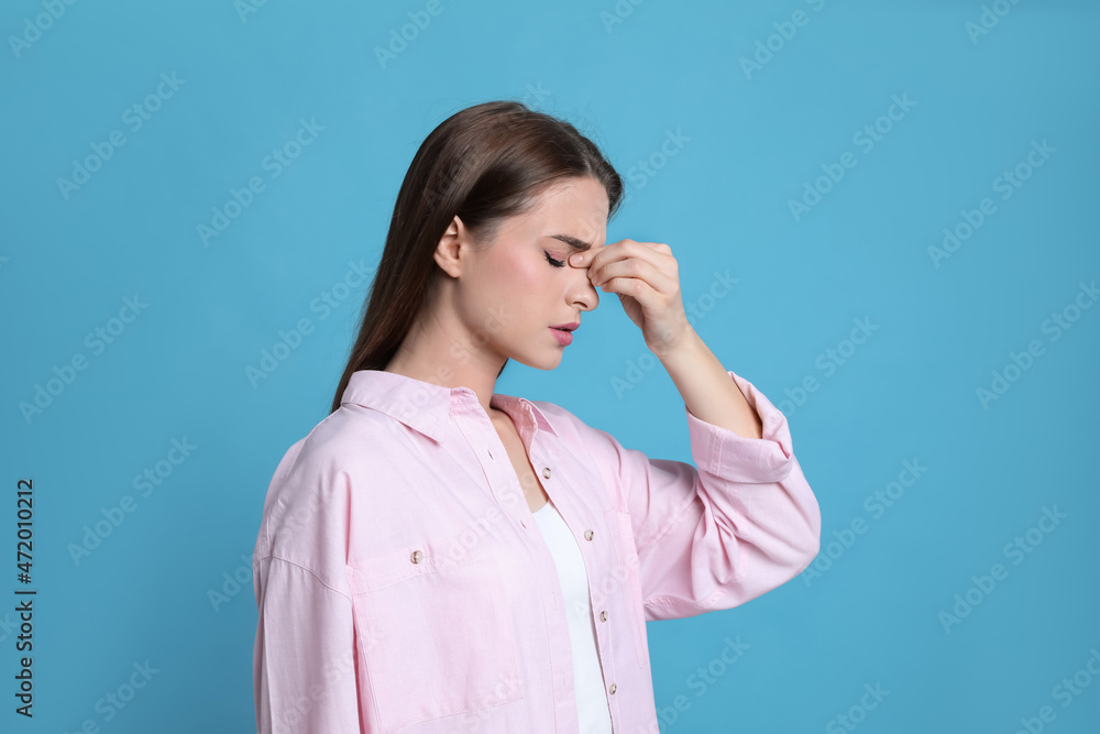 Young woman suffering from headache on light blue background Young woman suffering from headache on light blue background