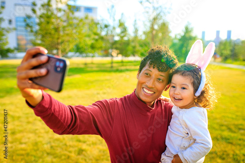 latin hispanic father and mixed race little girl taling selfie in rabbit and hare outdoor ear