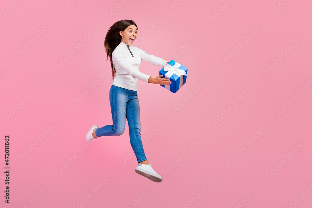 Full body photo of cool brunette small girl run gift present wear sweater jeans sneakers isolated on pink color background Full body photo of cool brunette small girl run gift present wear sweater jeans sneakers isolated on pink color background
