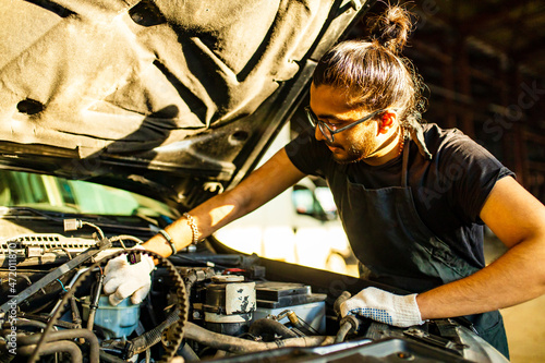 Photography indian man auto mechanic working indoors in car shop