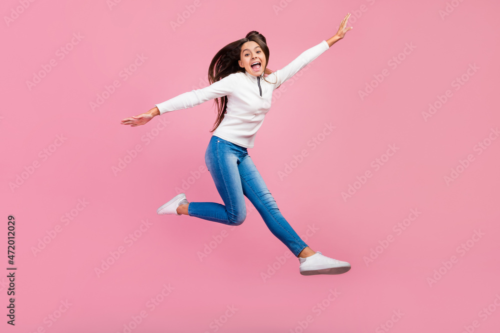 Full body profile photo of cute brunette teen girl jump wear sweater jeans shoes isolated on pink color background