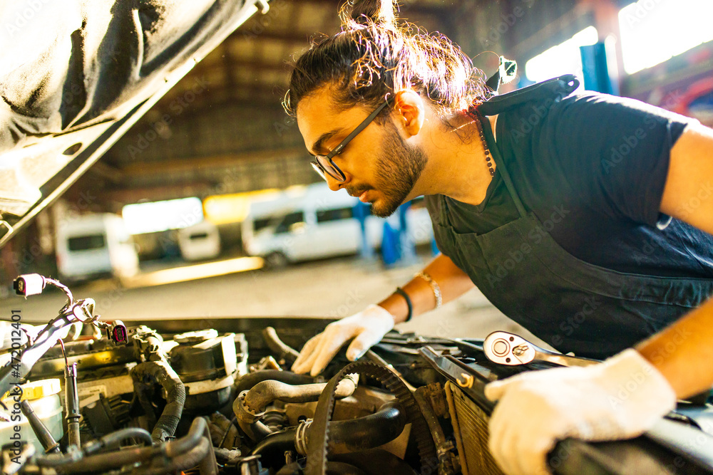 Auto mechanic standing in his workshop in sunset light background Auto mechanic standing in his workshop in sunset light background