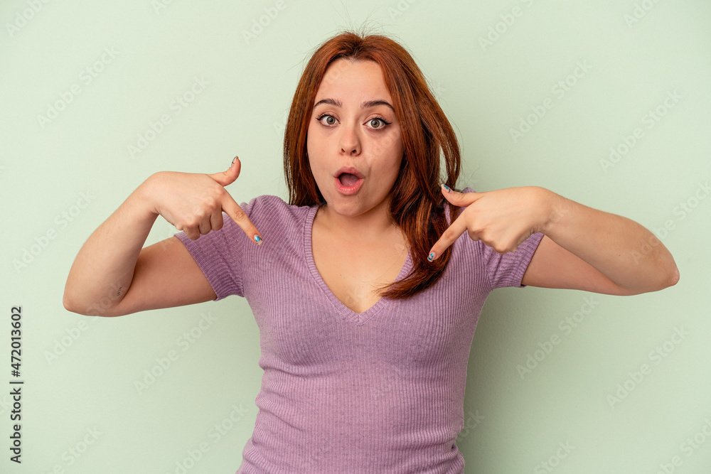 Fototapeta premium Young caucasian woman isolated on green background points down with fingers, positive feeling.