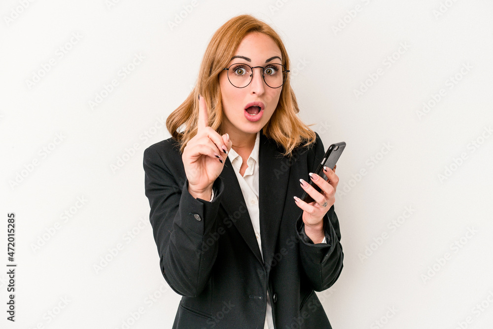 Young business caucasian woman holding mobile phone isolated on white background having an idea, inspiration concept. Young business caucasian woman holding mobile phone isolated on white background having an idea, inspiration concept.