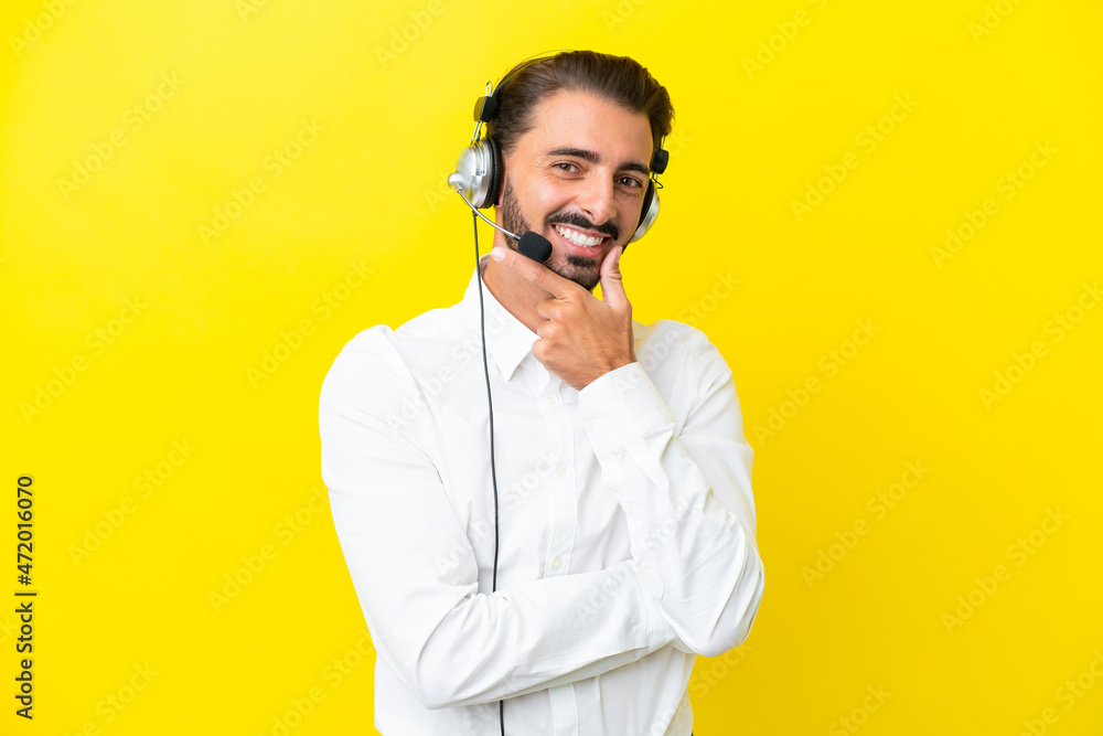 Telemarketer caucasian man working with a headset isolated on yellow background smiling Telemarketer caucasian man working with a headset isolated on yellow background smiling