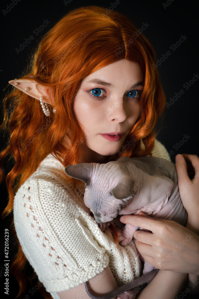 Portrait of cosplay elf young woman in white knitted dress holding ...