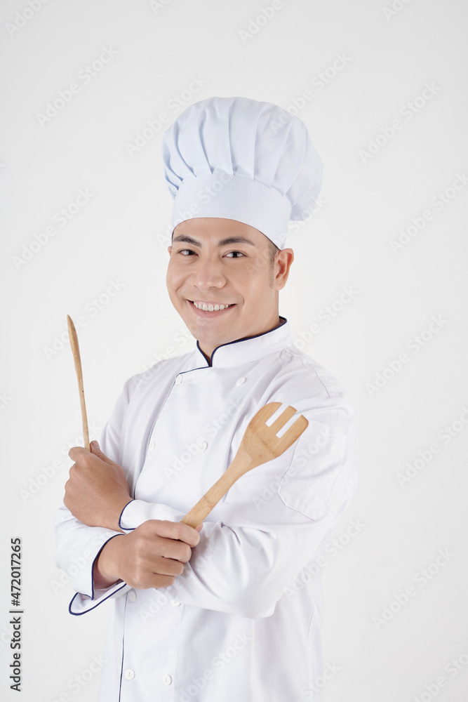 Studio portrait of smiling professional chef with wooden tools looking at camera Studio portrait of smiling professional chef with wooden tools looking at camera
