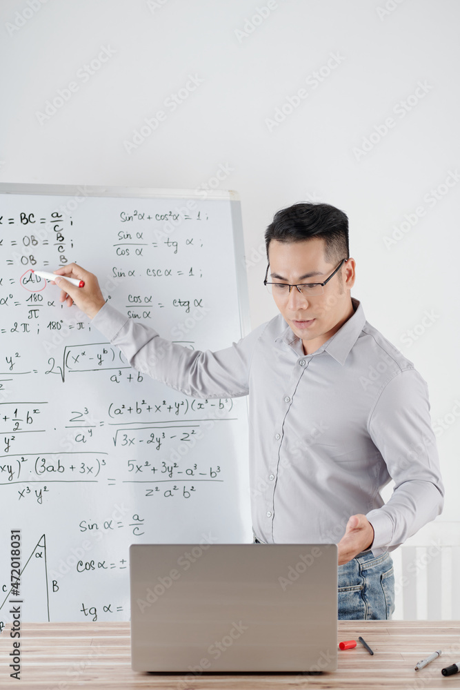 Tutor explaining math topic to student during online class, he is drawing formulas on whiteboard Tutor explaining math topic to student during online class, he is drawing formulas on whiteboard