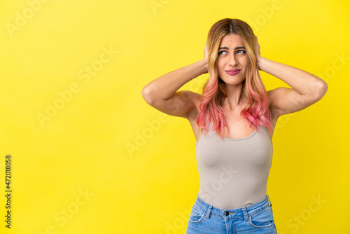 Young woman over isolated yellow background frustrated and covering ears