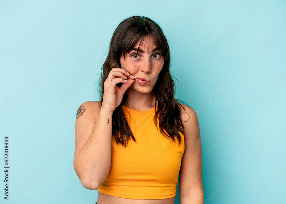 Young Argentinian woman isolated on blue background with fingers on lips keeping a secret. Young Argentinian woman isolated on blue background with fingers on lips keeping a secret.