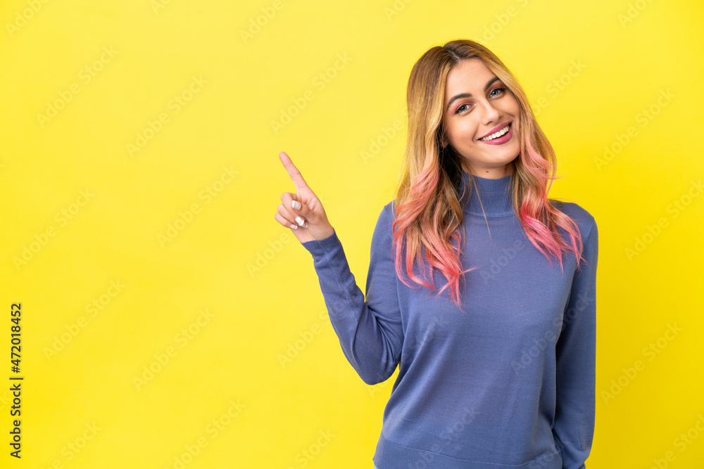 Young woman over isolated yellow background showing and lifting a finger in sign of the best Young woman over isolated yellow background showing and lifting a finger in sign of the best