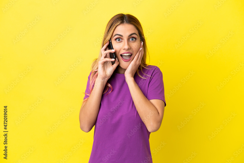 Young woman using mobile phone over isolated yellow background with surprise and shocked facial expression Young woman using mobile phone over isolated yellow background with surprise and shocked facial expression