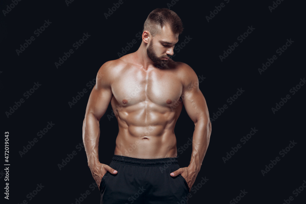 Muscular and fit young bodybuilder fitness male model posing isolated on black background