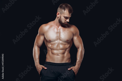 Muscular and fit young bodybuilder fitness male model posing isolated on black background