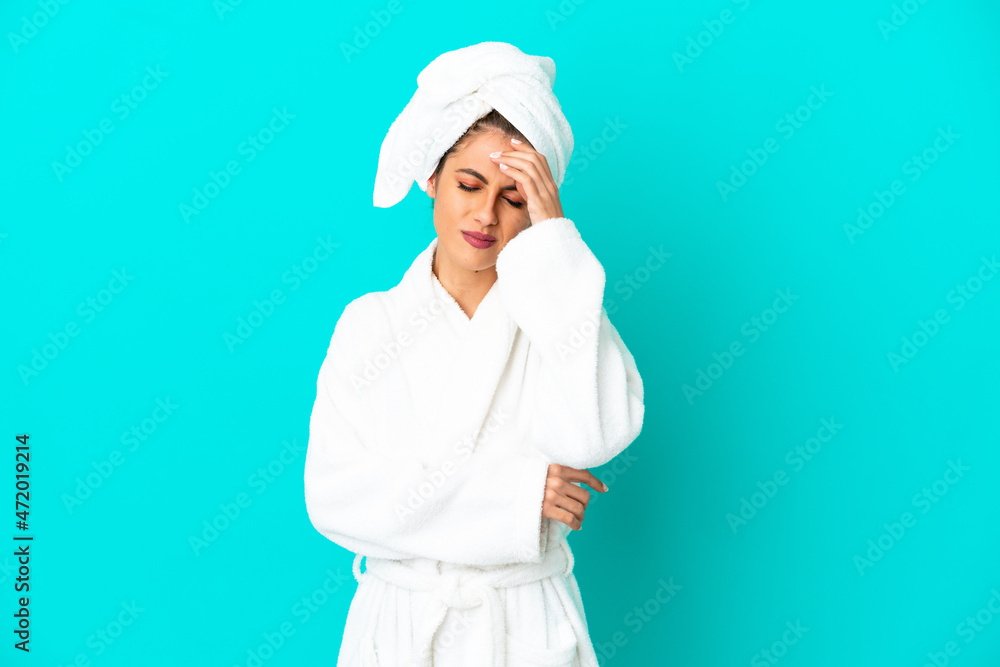 Young woman in a bathrobe over isolated blue background with headache Young woman in a bathrobe over isolated blue background with headache