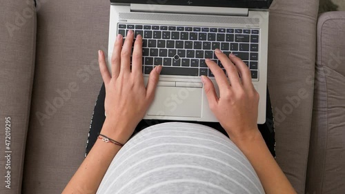 woman works on laptop sitting on couch during last trimester pregnancy