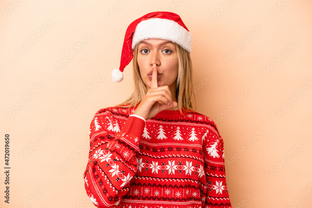 Young caucasian woman celebrating Christmas isolated on beige background keeping a secret or asking for silence. Young caucasian woman celebrating Christmas isolated on beige background keeping a secret or asking for silence.