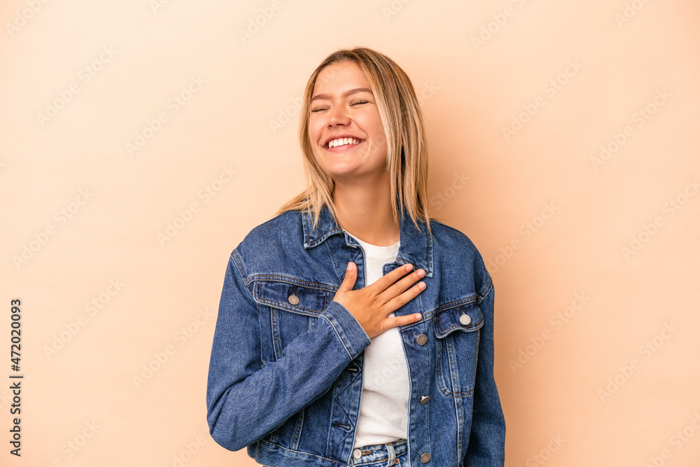 Young caucasian woman isolated on beige background laughing keeping hands on heart, concept of happiness. Young caucasian woman isolated on beige background laughing keeping hands on heart, concept of happiness.
