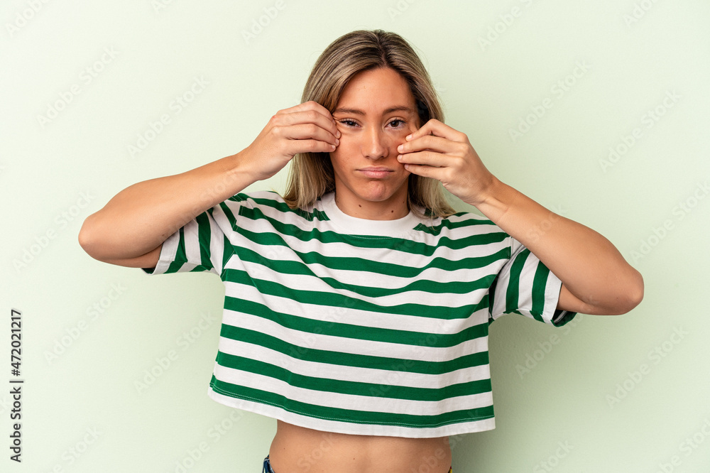 Young caucasian woman isolated on green background doubting between two options. Young caucasian woman isolated on green background doubting between two options.