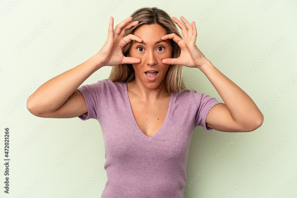 Young caucasian woman isolated on green background keeping eyes opened to find a success opportunity. Young caucasian woman isolated on green background keeping eyes opened to find a success opportunity.