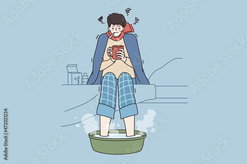 Fever and getting flu concept. Young sad man in warm clothes and scarf sitting with hot drink measuring temperature and making bath for foot vector illustration  © drawlab19