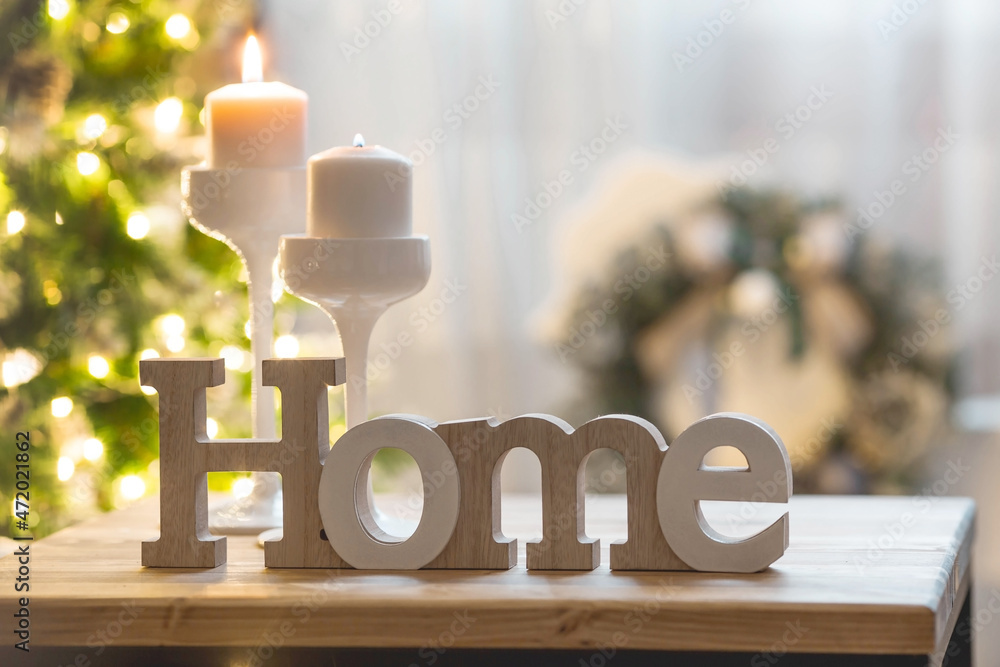© Юлия Клюева - The word home and burning candles in white candlesticks in the interior of the living room on the background of a Christmas tree.The concept of winter, festive home comfort and warmth. © Юлия Клюева - The word home and burning candles in white candlesticks in the interior of the living room on the background of a Christmas tree.The concept of winter, festive home comfort and warmth.