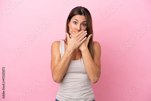 Middle age caucasian woman isolated on pink background covering mouth with hands