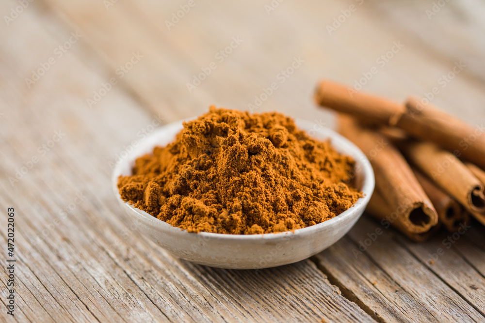 Ceylon cinnamon sticks with cinnamon powder in wooden bowl on concrete background. Ceylon cinnamon sticks with cinnamon powder in wooden bowl on concrete background.