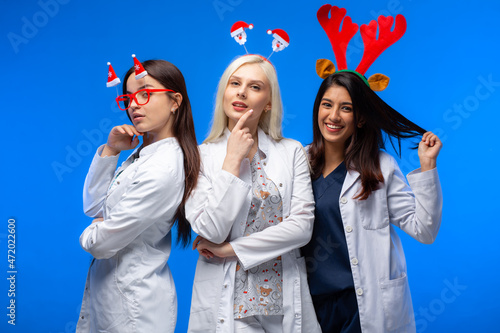 A group of doctors celebrates winter holidays in the studio. Three beautiful girls doctors of different nations wish Merry Christmas. Happy New Year!