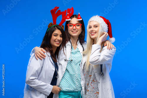 A group of doctors celebrates winter holidays in the studio. Three beautiful girls doctors of different nations wish Merry Christmas. Happy New Year!