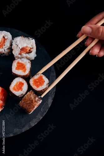 table black various sushi with hand on hashi