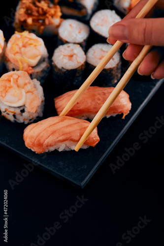 table black various sushi with hand on hashi