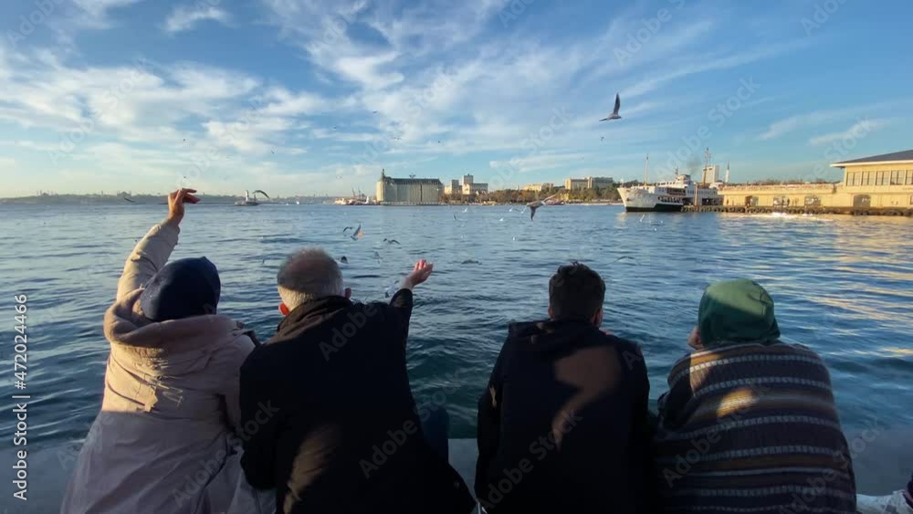 A couple feed seagulls during a sunny afternoon in the Kadikoy pier, located at the Asian side of Istanbul city, Turkey. A couple feed seagulls during a sunny afternoon in the Kadikoy pier, located at the Asian side of Istanbul city, Turkey.