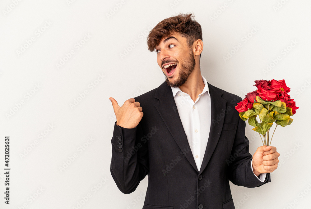 Young mixed race man holding bouquet of roses isolated on white background points with thumb finger away, laughing and carefree. Young mixed race man holding bouquet of roses isolated on white background points with thumb finger away, laughing and carefree.