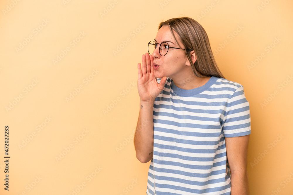 Young caucasian woman isolated on yellow background is saying a secret hot braking news and looking aside Young caucasian woman isolated on yellow background is saying a secret hot braking news and looking aside