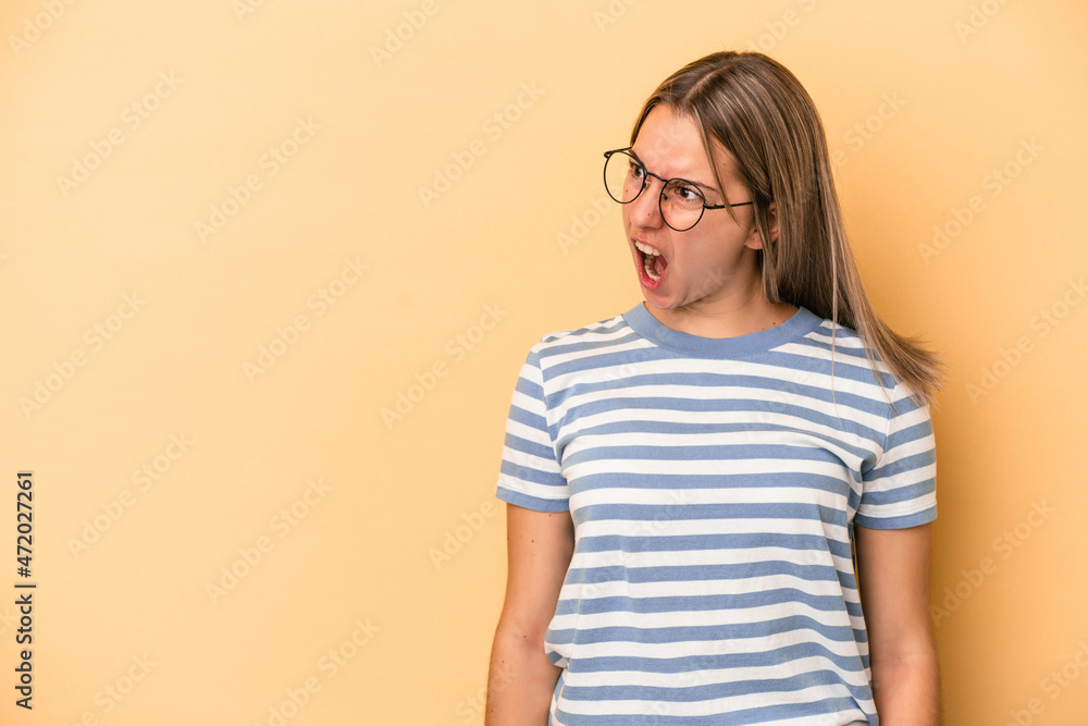 Young caucasian woman isolated on yellow background shouting very angry, rage concept, frustrated. Young caucasian woman isolated on yellow background shouting very angry, rage concept, frustrated.