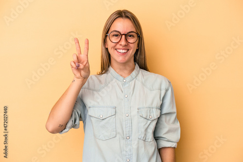 Young caucasian woman isolated on yellow background showing number two with fingers.