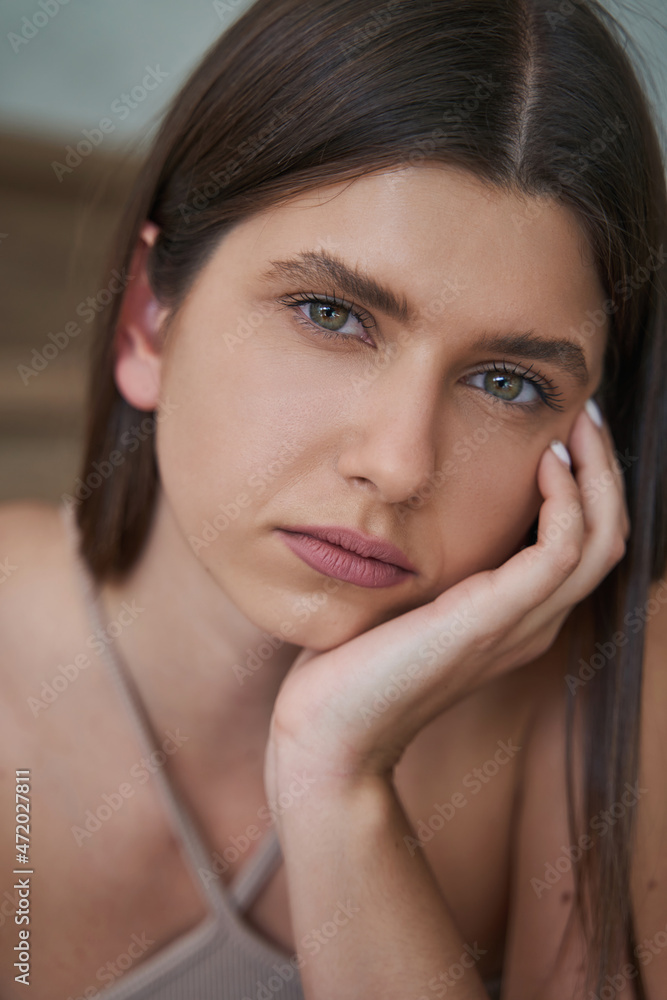 Despondent woman leaning her cheek on hand and staring ahead Despondent woman leaning her cheek on hand and staring ahead