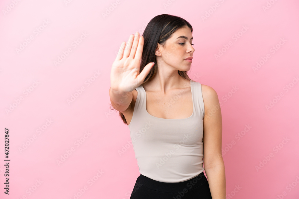 Young Italian woman isolated on pink background making stop gesture and disappointed Young Italian woman isolated on pink background making stop gesture and disappointed