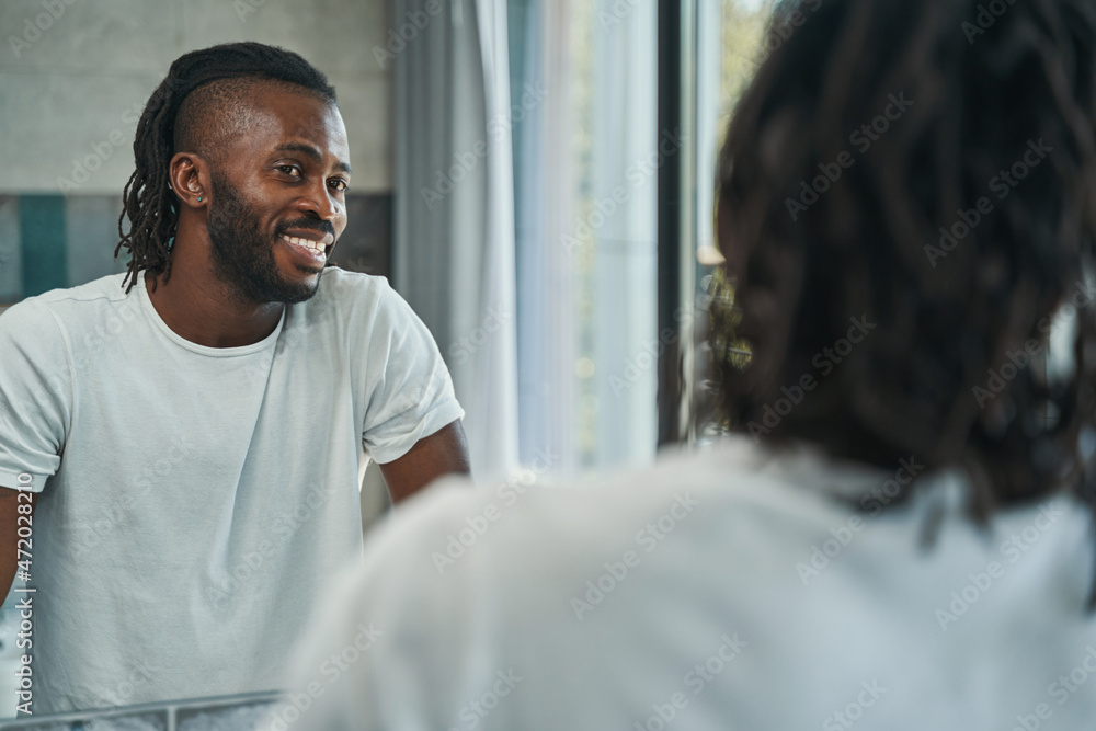 Joyous man admiring his appearance in bathroom Joyous man admiring his appearance in bathroom
