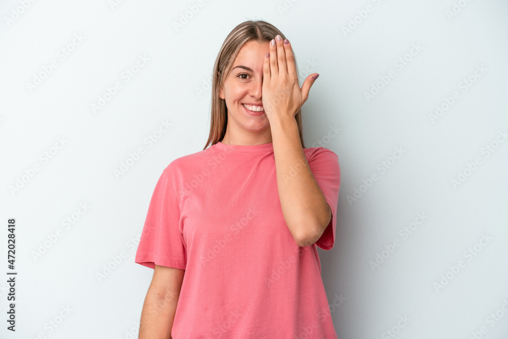 Young caucasian woman isolated on blue background having fun covering half of face with palm. Young caucasian woman isolated on blue background having fun covering half of face with palm.