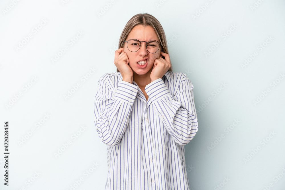 Young caucasian woman isolated on blue background covering ears with hands. Young caucasian woman isolated on blue background covering ears with hands.