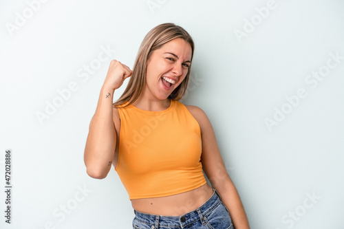 Young caucasian woman isolated on blue background celebrating a victory, passion and enthusiasm, happy expression.