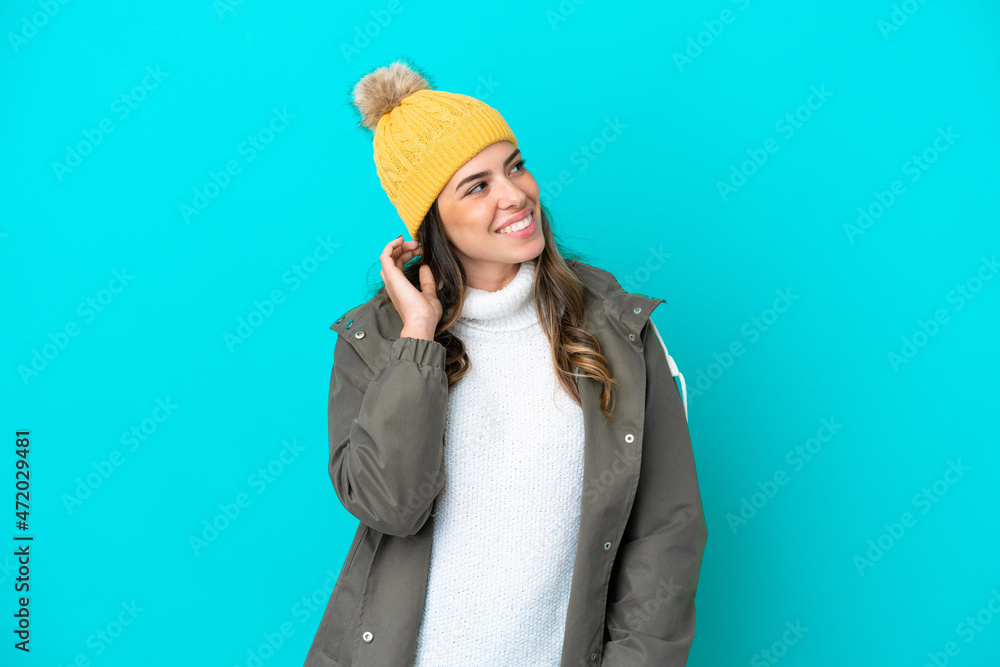 Young Italian woman wearing winter jacket and hat isolated on blue background thinking an idea Young Italian woman wearing winter jacket and hat isolated on blue background thinking an idea
