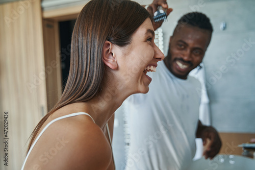 Smiling man shaving laughing woman forehead in bathroom